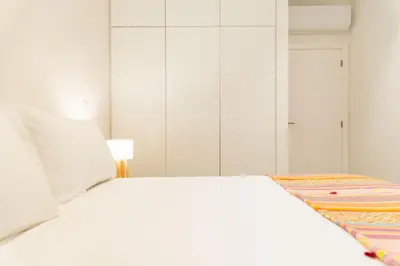 a white bed in a white bedroom with a lamp at Apartamentos Fernão de Ornelas by Heart of Funchal in Funchal