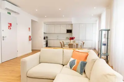 a living room with a white couch and a kitchen at Apartamentos Fernão de Ornelas by Heart of Funchal in Funchal