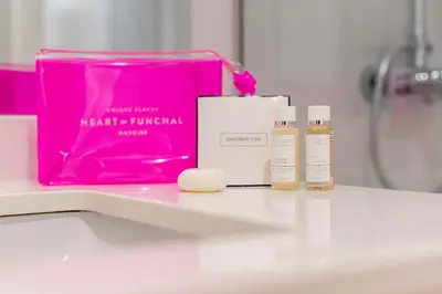 a pink bag sitting on a bathroom counter with three products at Apartamentos Fernão de Ornelas by Heart of Funchal in Funchal