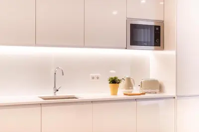 a white kitchen with a sink and a microwave at Apartamentos Fernão de Ornelas by Heart of Funchal in Funchal