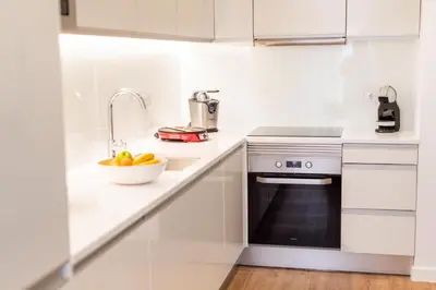 a white kitchen with a sink and a bowl of fruit at Apartamentos Fernão de Ornelas by Heart of Funchal in Funchal