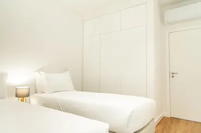 a white bedroom with two beds and a mirror at Apartamentos Fernão de Ornelas by Heart of Funchal in Funchal