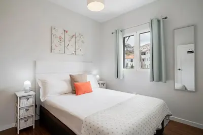a bedroom with a white bed with an orange pillow on it at Terrace Vila by An Island Apart in Caniço