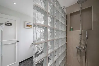 a glass block wall in a bathroom with a shower at Terrace Vila by An Island Apart in Caniço