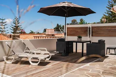 a patio with an umbrella and a table and chairs at Terrace Vila by An Island Apart in Caniço
