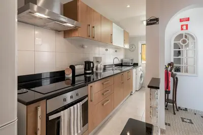 a large kitchen with wooden cabinets and appliances at Terrace Vila by An Island Apart in Caniço