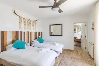 two beds in a room with white walls and blue pillows at Vida Boa Lodge in Lagos