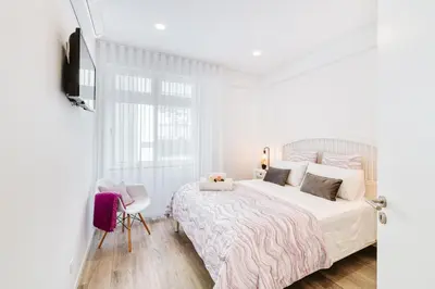 a white bedroom with a bed and a chair at Os Fragosinhos by Amazing Madeira in Funchal
