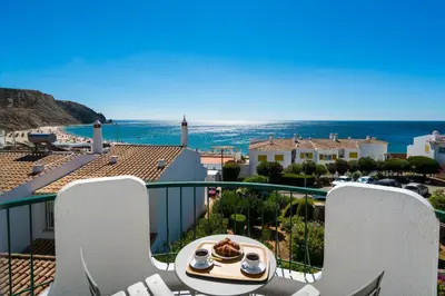 a table and chairs on a balcony with a view of the ocean at Waterside Village - Sea View Apartment in Alagoas