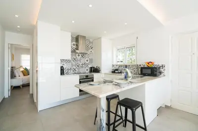 a kitchen with white cabinets and a counter with stools at Waterside Village - Sea View Apartment in Alagoas