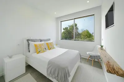 a white bedroom with a large bed and a window at Casa da Maloeira by An Island Apart in Fajã da Ovelha