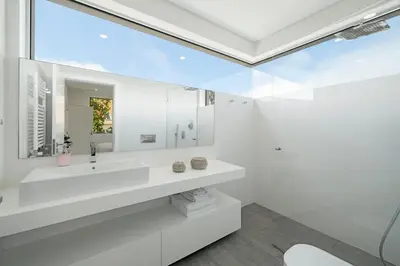 a white bathroom with a sink and a mirror at Casa da Maloeira by An Island Apart in Fajã da Ovelha