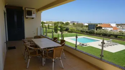 a balcony with a table and chairs and a swimming pool at Apartamento 7 Mares com 2 Quartos in Sagres