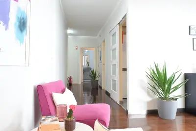 a living room with a pink chair and a table at Design Gardens, a Home in Madeira in Funchal