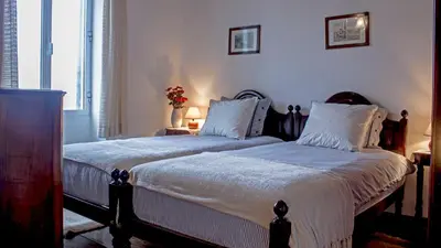 a bedroom with two beds with white blankets and pillows at Vila Joaninha in Santo da Serra