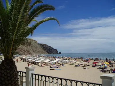 a crowd of people on a beach with umbrellas at Vilamar in Luz