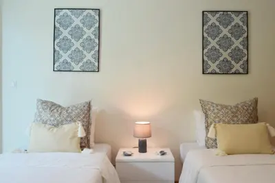 a bedroom with two beds and a table with a lamp at Machico Beach, a Home in Madeira in Machico