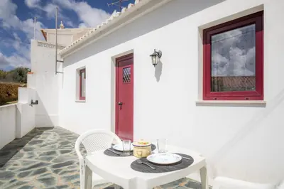 a white house with a white table and a red door at C14 - Casa da Luz in Luz