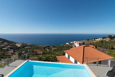 a villa with a swimming pool and a view of the ocean at Luxo & Conforto in Calheta
