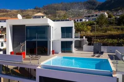 a villa with a swimming pool on top of a house at Luxo & Conforto in Calheta