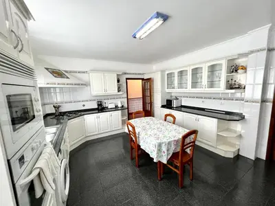a kitchen with white cabinets and a table with chairs at Classic Tranquil Madeiran 4-Bedroom Villa Funchal in Funchal