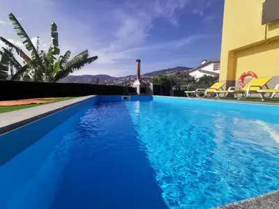 a blue swimming pool with chairs next to a building at CASA DOS AVÓS Apartments with Pool in Funchal in Funchal
