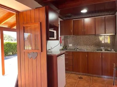 a kitchen with wooden cabinets and a microwave at Zef's Cottage in São Vicente
