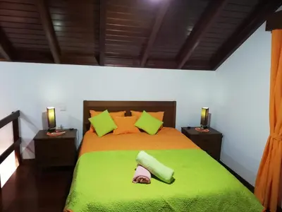 a bedroom with a bed with a green blanket and pillows at Zef's Cottage in São Vicente
