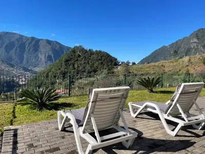 two rocking chairs on a patio with mountains in the background at Zef's chalet in Senhora do Rosário