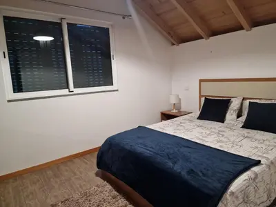 a bedroom with a large bed and two windows at Zef's chalet in Senhora do Rosário