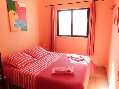 a red bedroom with a bed with red and white stripes at Casa do Lado in Carrapateira