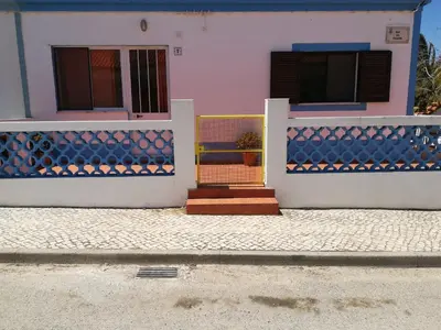 a house with blue and white walls and a gate at Casa do Lado in Carrapateira