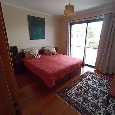 a bedroom with a bed with a red bedspread and a window at The Goat's Place in Gaula