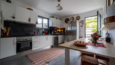 a kitchen with white cabinets and a wooden table at The Goat's Place in Gaula