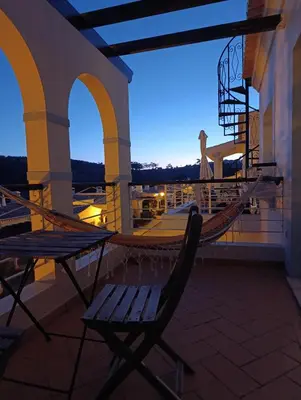 a hammock and a chair on a balcony at night at Komfortables Town House in traumhafter Lage in Budens