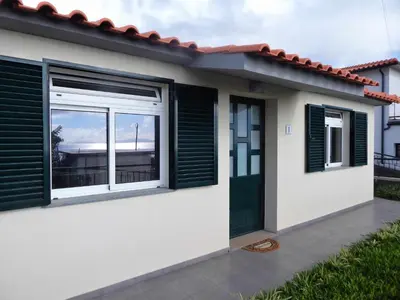 a house with green shutters and a window at Villas Madalena Chalets vista mar cWiFi in Santa Cruz