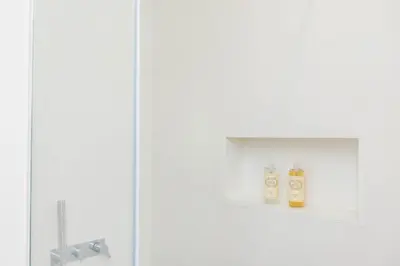 a white bathroom with two bottles of soap on a shelf at Golden Sea Horizon in Funchal