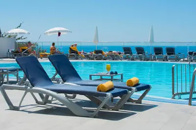 a group of lounge chairs next to a swimming pool at Golden Sea Horizon in Funchal