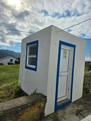 a small white building with a blue door at casa Eira Alta in Santa Bárbara