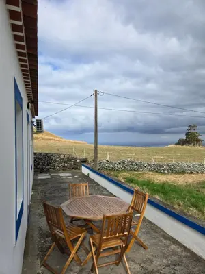 a wooden table and chairs on a porch with a view of the ocean at casa Eira Alta in Santa Bárbara