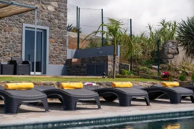 a group of chairs and a pool in front of a house at Villa Fauna - Nature & Tranquility - Heated pool optional in Prazeres