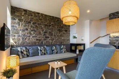 a living room with a blue couch and a stone wall at Villa Fauna - Nature & Tranquility - Heated pool optional in Prazeres