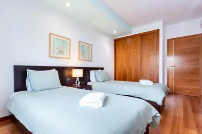 two beds in a hotel room with white sheets at Baia da Luz - Great Light apartment in Luz
