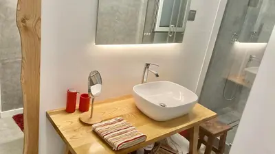 a bathroom with a sink and a mirror on a table at Cristalia,Roof terrace in city center, Garage, Netflix 75inch TV in Funchal