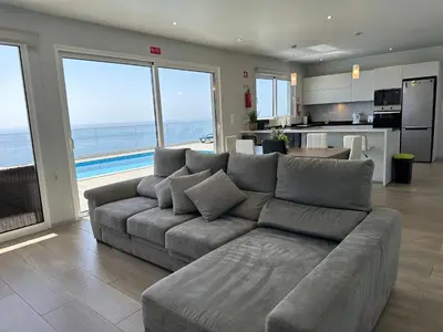 a living room with a gray couch and a kitchen at Casa Bela Vista in Venda do Atalhinho