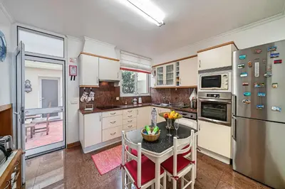 a kitchen with a table and a refrigerator at OurMadeira - Moradia da Falésia in Câmara de Lobos