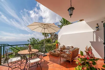 a patio with a table and chairs and an umbrella at OurMadeira - Moradia da Falésia in Câmara de Lobos