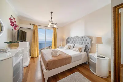 a white bedroom with a bed and a window at OurMadeira - Moradia da Falésia in Câmara de Lobos