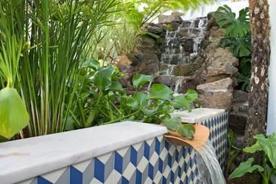 a garden with a waterfall and a stone wall at OurMadeira - Villa do Mar IV in Calheta