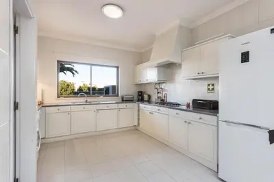 a kitchen with white cabinets and a window at Casa da Ermida in Budens
